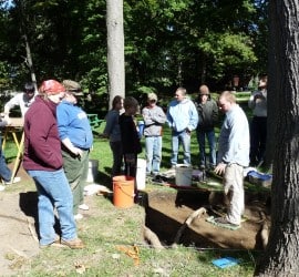 Dr. Chris Moore (right) explains the find to his students and members of the public participating in History Beneath Us.