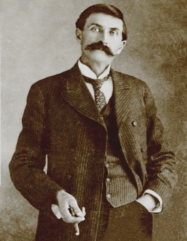 Pat Garrett, the man who shot Billy the Kid. Garrett slouches with one hand in his pocket, the other holding a cigar.