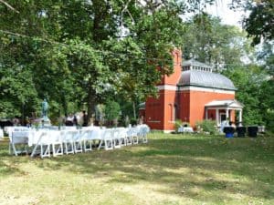 White chairs set up on the lawn for weddings with General Lew Wallace's orange brick Study building in the background