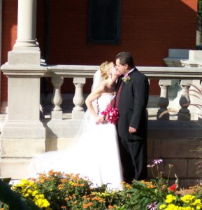 A bride and groom kiss after their wedding in front of the limestone porch of Lew Wallace's Study building
