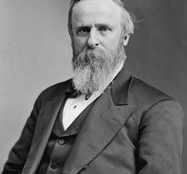 Portrait of President Rutherford B. Hayes; he has a long beard and is seated.