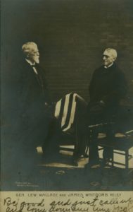 Two men, James Whitcomb Riley and Lew Wallace, stand in front of a brick wall. They are facing each other with a chair between them.