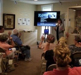 Joan Hostetler gives an historic photo lecture to a group in the Carriage House