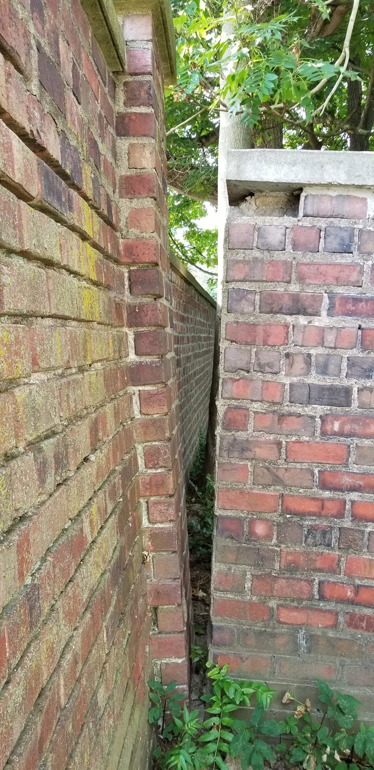 Wall restoration needed: Two brick walls meet; one is leaning significantly.
